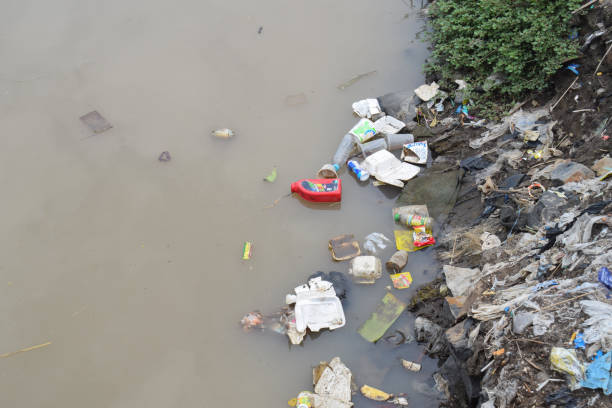 Pasuruan, 26 October 2022 - Plastic bottles, cans, packages and other river waste. Garbage in the River