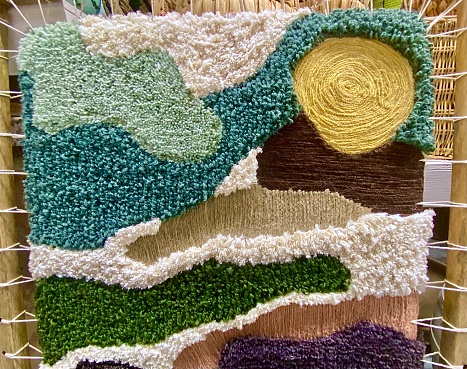 close up of part of handmade creative textile art design of landscape with sun and land art created from cotton wool and other fabricsHorizontal