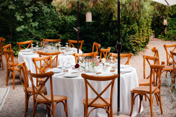 istock Backyard wedding reception - round tables with white tablecloths, vintage lanterns, roses and hyacinth,  and bentwood chairs 1449763645