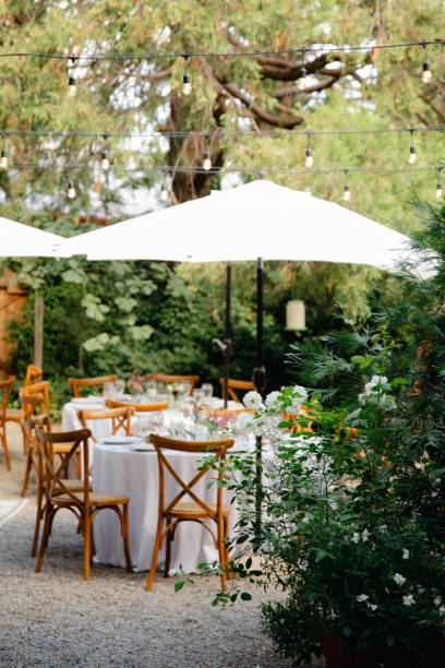 istock Backyard wedding reception - round tables with white tablecloths, vintage lanterns, roses and hyacinth,  and bentwood chairs 1449763749