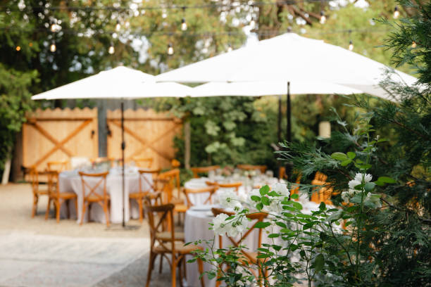 istock Backyard wedding reception - round tables with white tablecloths, vintage lanterns, roses and hyacinth,  and bentwood chairs 1449763786