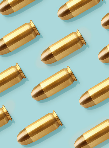 Looking down on group of bullets lined up on a pastel colored background