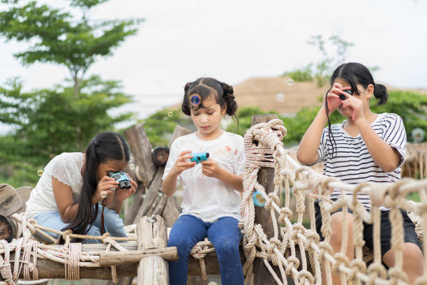 Group of children kids girl exploring nature through magnifying glass and binoculars on outdoor playground. Education, field trips, researcher and discovery concept Group of children kids girl exploring nature through magnifying glass and binoculars on outdoor playground. Education, field trips, researcher and discovery concept career exploration kids stock pictures, royalty-free photos & images