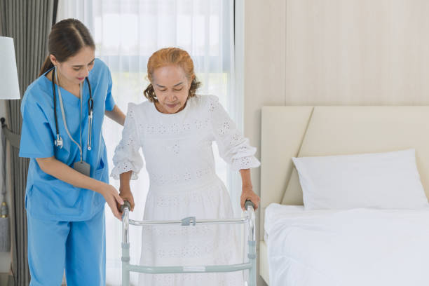 istock Asian elderly senior woman using walker aid with nurse care support step walking at home. 1449766269