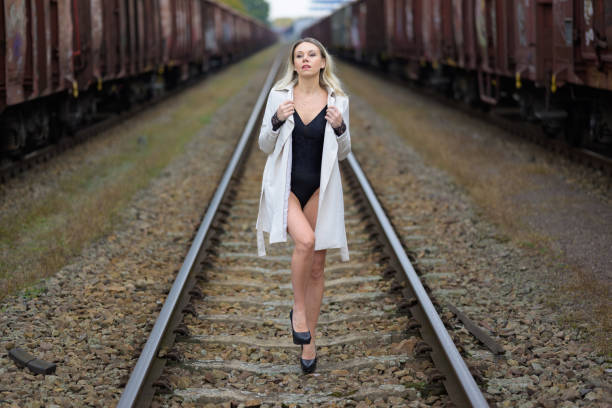 istock Woman in a white trench coat standing on train tracks 1449766399
