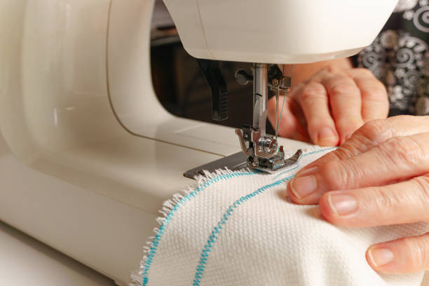 istock woman's hands sewing fabric on a sewing machine 1449767129