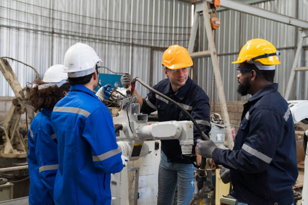 gruppe von ingenieurarbeitern diskutieren und arbeiten, überprüfen, reparieren, warten automatische schweißroboterarmmaschine an der produktionslinie in der industriefabrik - welder manual worker african descent steel worker stock-fotos und bilder