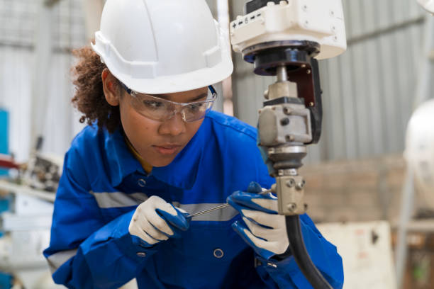 trabalhadora engenheira usando a máquina de braço robótico de soldagem automática de manutenção de chave de fenda na fábrica. mulher técnica trabalhador verificando, reparar a máquina de braço do robô de soldagem automática na linha de produç� - cnc vehicle part quality control industry - fotografias e filmes do acervo