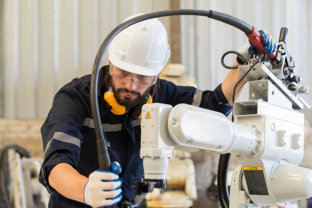 istock Male engineer worker working with automatic welding robotic arm machine in factory. Male technician worker checking, repair automatic welding robot arm machine at production line 1449769316