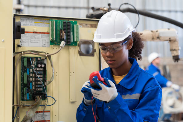 operaia elettricista che controlla, ripara, manutenzione del sistema elettrico in fabbrica. ingegnere elettricista donna che lavora con il sistema elettrico di funzionamento presso la linea di produzione - elettricista foto e immagini stock