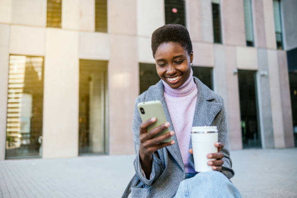 istock Cheerful black woman using smartphone on street 1449769478