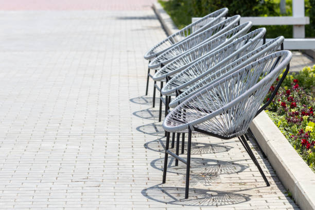 round wicker chairs on the pavement, chairs for outdoor seating. waiting area, empty seats