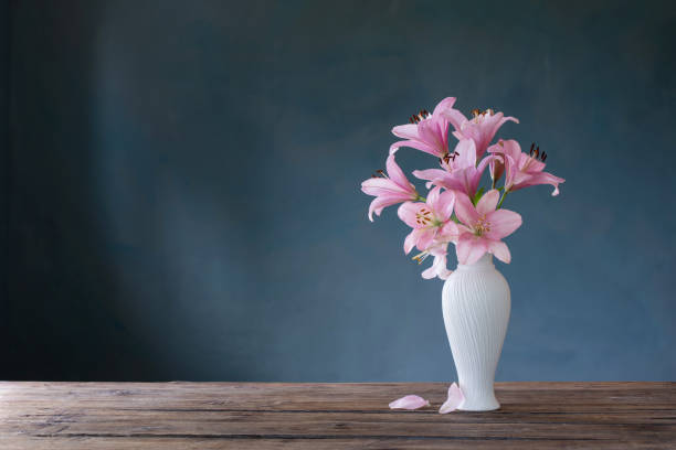 istock pink lily in white vase on blue background 1449775641