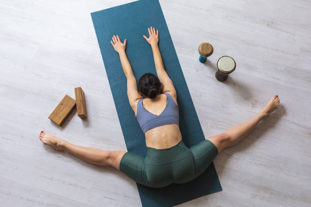 istock Young woman practicing yoga, performs samokanasana exercise, transverse twine with body tilt forward, lies on mat in studio, top view 1449776523