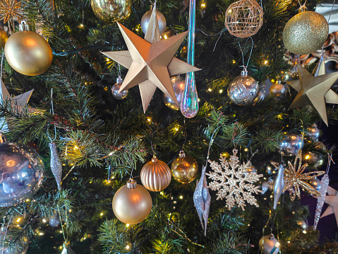 Close-up shot of beautiful gold and silver christmas decoration hanging on christmas tree
