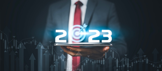 Businessman holds tablets with target and number new year 2023 on the business graph background, Innovative new ideas of inspiration from online technology, Changes in new planning, Business Growth