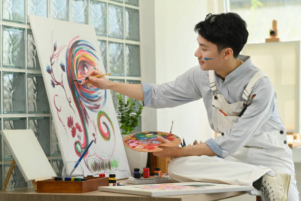 istock Pleasant man artist creating artwork with watercolor on canvas, enjoy creativity activity at home. Art and leisure activity concept. 1449780338