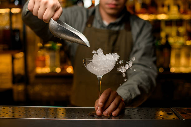 istock front view of wine glass into which the hand of bartender pours ice cubes using scoop. 1449782369