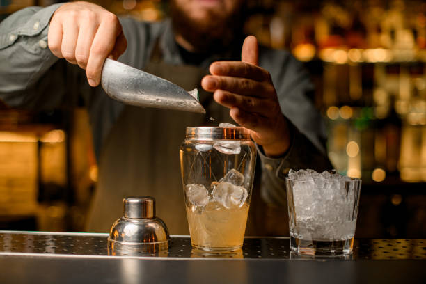 istock front view of shaker with drink into which bartender pours ice cubes using scoop 1449783009
