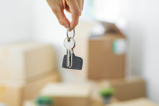 Woman holding a set of house keys on a cardboard box during moving