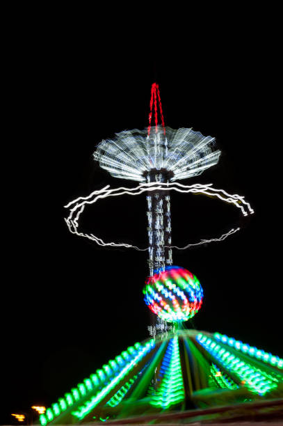 atração iluminada rotativa no parque de diversões à noite. efeito de movimento. - ferris wheel wheel blurred motion amusement park - fotografias e filmes do acervo