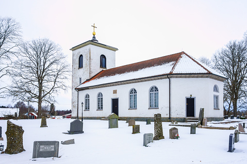 Ullene, Sweden - February 15, 2021: Country church with snow in the cemetery