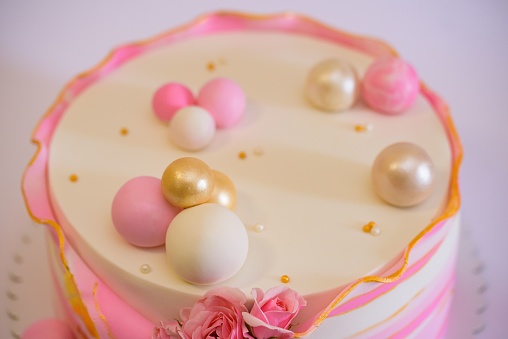 A closeup of a cake decorated with pink roses and balls