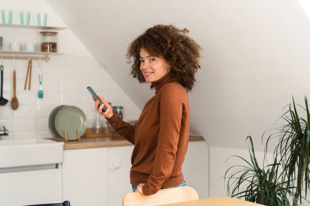 istock Portrait of a young woman using smartphone at her kitchen 1449788123
