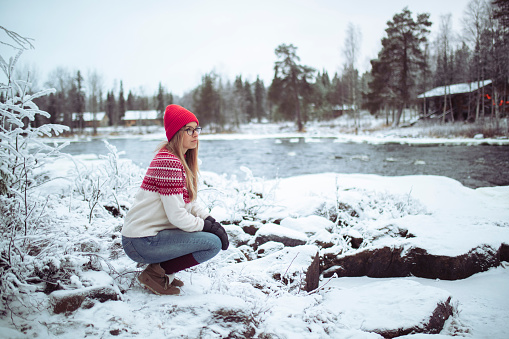 A woman is on the shore looking at nature during a winter, snowy day