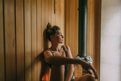 Photo of a young woman relaxing in sauna she is at and enjoying her spa day