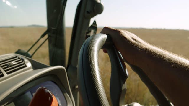 hand of unrecognizable driver in combine harvester on steering wheel. combine harvester is employee who drives tractor or combine, agricultural machinery and harvests or plows land.