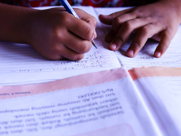 istock male student writing in a book on the table. Selective focus. 1449802147