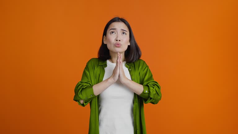 Young Asian woman makes wish folding hands in prayer gesture