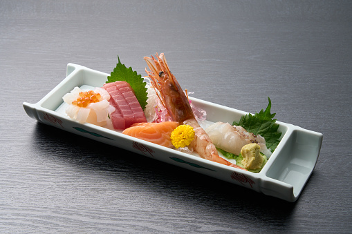 Japanese Omakase meal: Aging Raw Akami Tuna Sushi adds with sliced truffle served by hand on a stone plate. Japanese traditional and luxury meal.