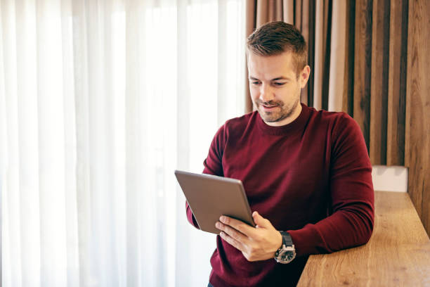 istock A contemporary millennial is scrolling on the tablet while standing at home. 1449805952