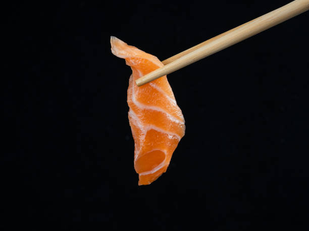 istock Salmon sashimi with chopsticks on black background 1449810029