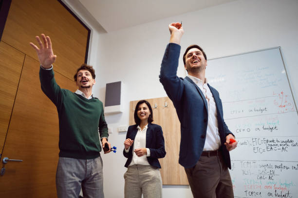Business people playing darts at the office and having fun together