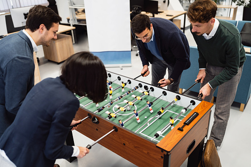 Business people playing table football at the office and having fun together.
