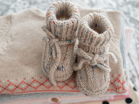 Knitted socks, knitted children's shoes made of natural wool, handmade lie on children's knitted things. Warmth and comfort for newborns.