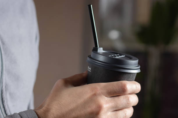 istock Man drinking coffee from disposable cup with cocktail tube close up 1449816516