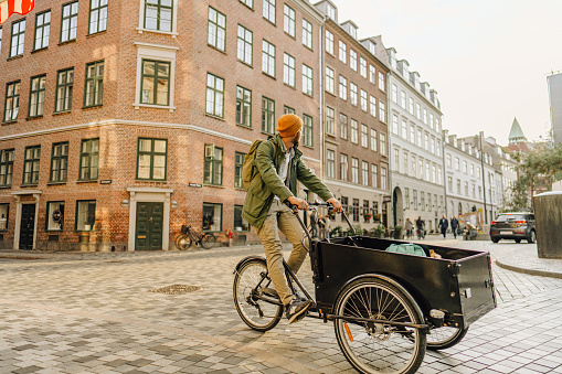 Photo of a man riding his cargo bike around the city.