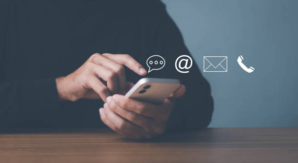 istock Man use smartphone contact us or e-mail marketing concept, Customer support hotline Contact us people connection. cube wood with the email, call phone, address, Chat message icons. on keyboard computer. 1449822179