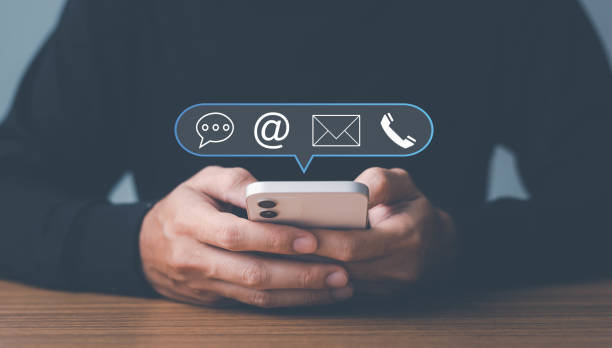 istock Man use smartphone contact us or e-mail marketing concept, Customer support hotline Contact us people connection. cube wood with the email, call phone, address, Chat message icons. on keyboard computer. 1449822387