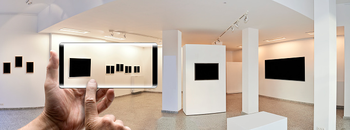 Male hand shoot with smartphone in a exhibition gallery, wall mounted art with museum style lighting