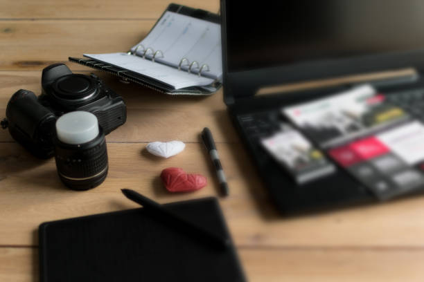 Graphic designer workstation with dslr, lens, laptop, agenda, stylus and 3d objects