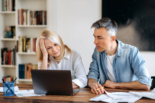 istock Frustrated, tired, two business partners, sitting at a workplace, working on a new project, discussing work issues, sorting out documents, develop strategy or new start up, focused looking at a laptop 1449829436