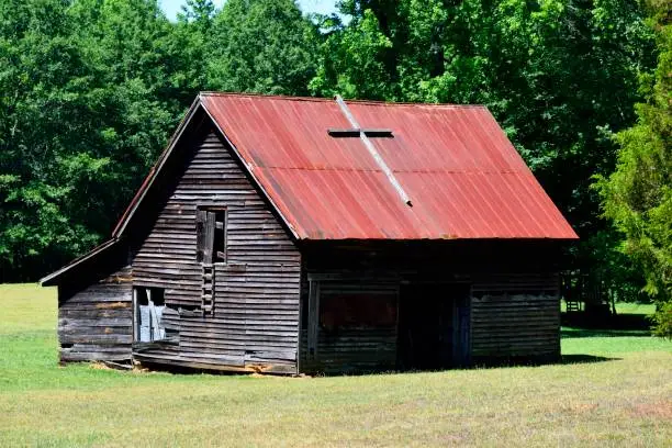 Rustic barn shed at farm rural Georgia, USA with cross on top of a metal roof.