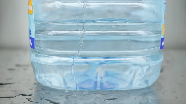 Pure water is poured into a large plastic bottle.