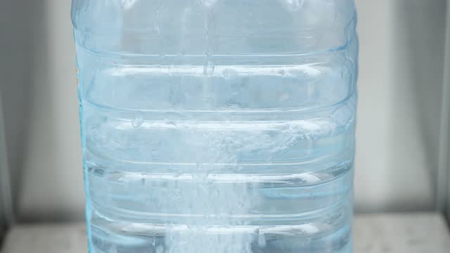 Pure water is poured into a large plastic bottle.