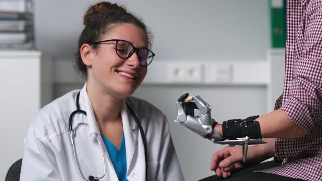 Young female therapist examine patient moving bionic hand prosthesis in hospital